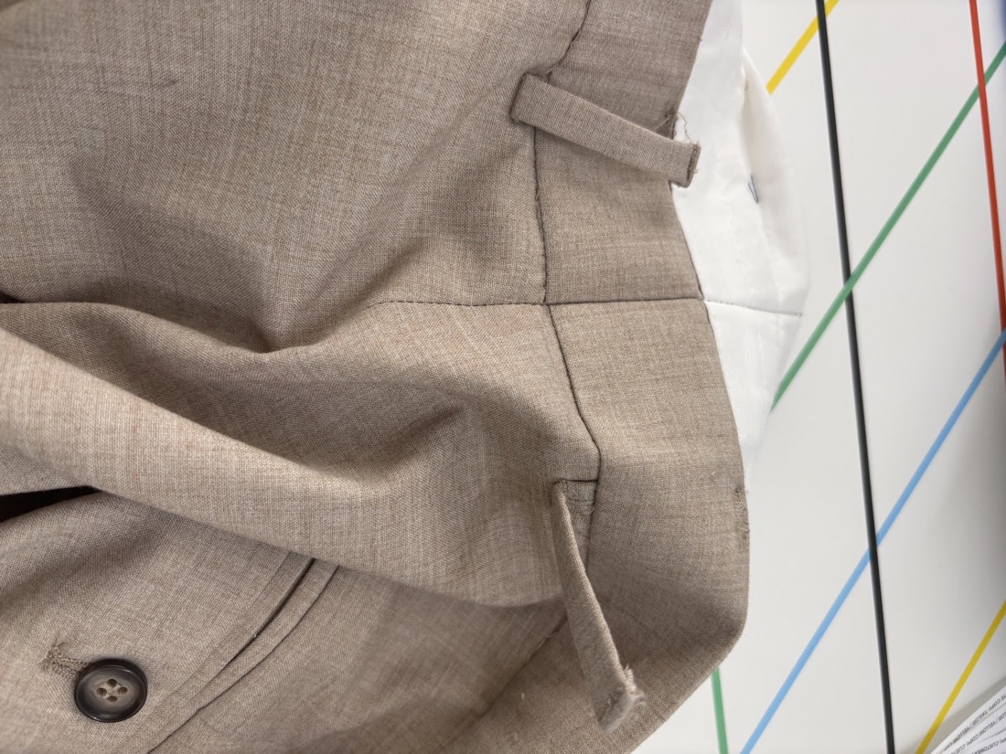 Close-up of a taupe trouser waistband and belt loop hand-finished at Craft Tailors